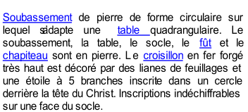 Soubassement  de pierre de forme circulaire sur  lequel sadapte une  table  quadrangulaire. Le  soubassement, la table, le socle, le  ft  et le  chapiteau  sont en pierre. L e  croisillon  en fer forg   trs haut est dcor par des lianes de feuillages et  une toile  5 branches inscrite dans un cercle  derrire la tte du Christ. Inscriptions indchiffrables  sur une face du socle.